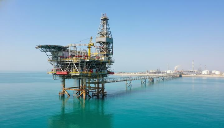 Морская газовая платформа со скважинами в открытом море. Трубопроводы ведут к промышленному комплексу на острове на горизонте.